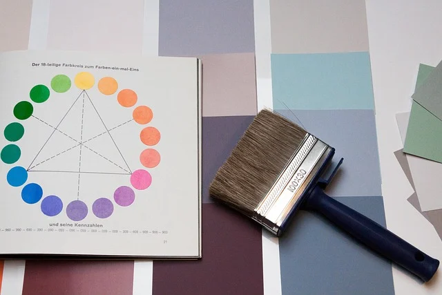 A paint brush on color swatches next to a color wheel book