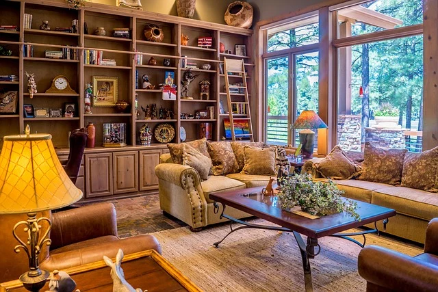 A cozy living room with wooden bookshelves, sofas, and large windows