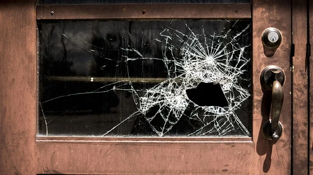 A shattered glass window on a wooden door with a lock