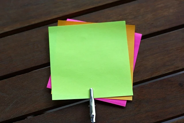 Colorful sticky notes clipped together on a wooden surface