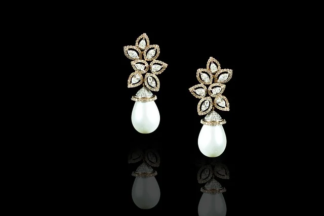 A pair of diamond and pearl drop earrings on a black background