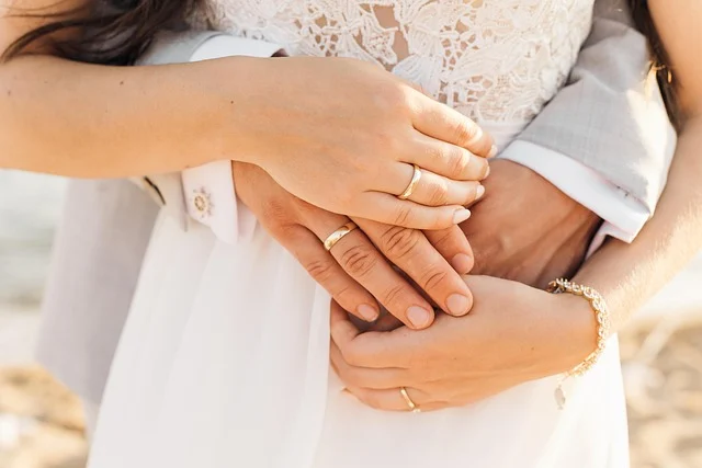 A couple embracing and showing gold wedding bands on their hands