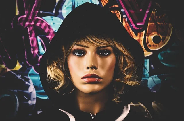 Essentials: A mannequin wearing a black hoodie against a colorful graffiti background