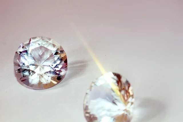 Two round brilliant-cut clear gemstones resting on a light background