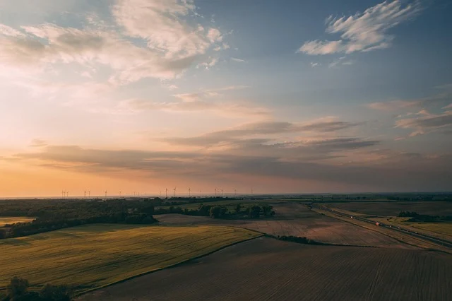 Aerial landscape view of fields and wind turbines at sunset