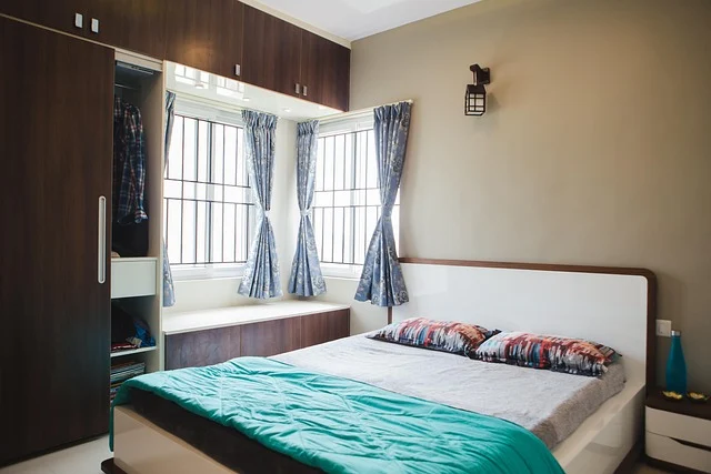 A modern bedroom with a bed, wardrobe, and windows