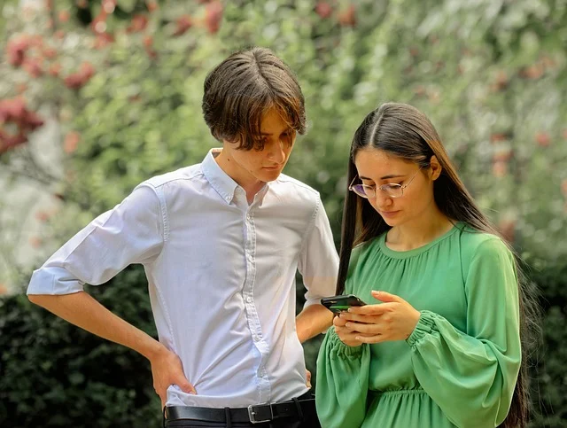 Two young people looking at a smartphone together outdoors