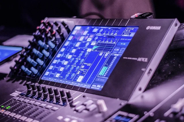 A close-up of a digital Yamaha audio mixing console with illuminated screen
