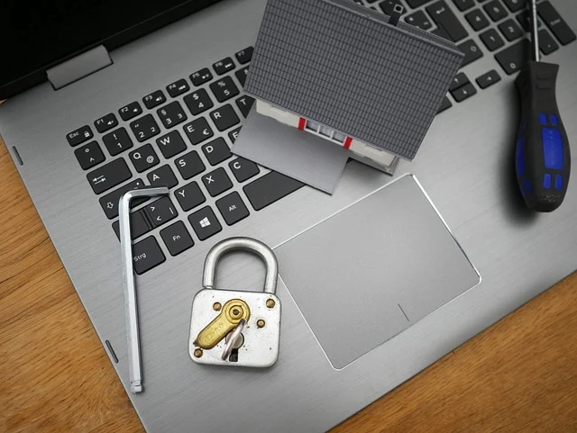 A padlock, miniature house model, and tools on a laptop keyboard