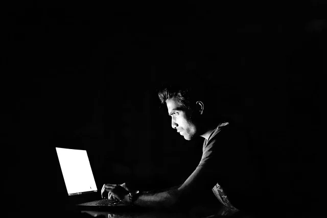 A person working on a laptop in a dark room