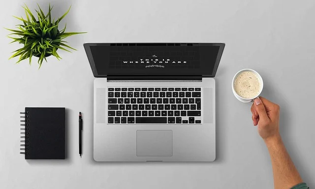 Overhead view of a laptop, coffee cup, and notebook on a desk