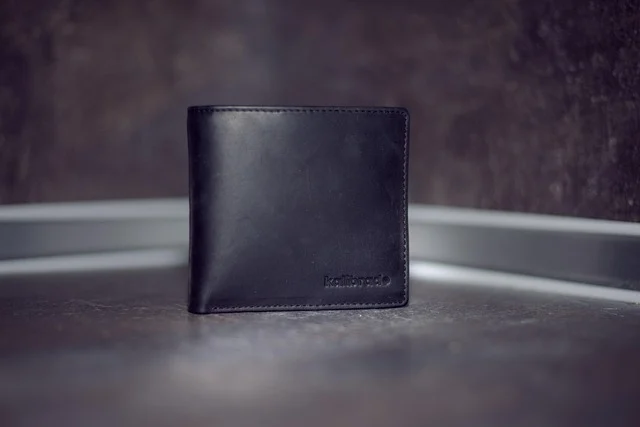 A black leather wallet standing on a dark surface