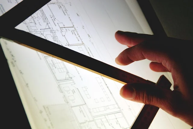 A hand measuring architectural blueprints on a illuminated lightbox