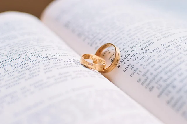 Two gold wedding bands resting on the pages of an open book
