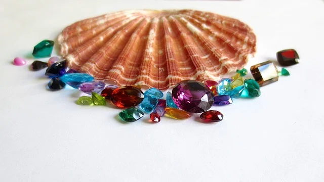 Colorful loose gemstones displayed in front of a seashell