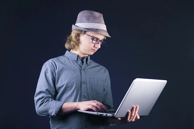 A young man wearing a hat using a laptop