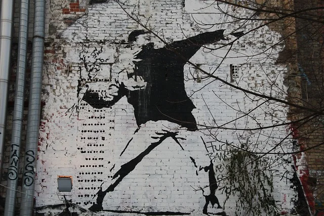 Banksy style stencil graffiti of a protester on a brick wall