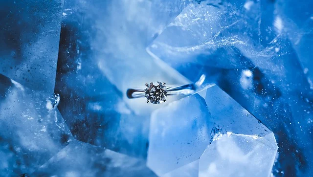 A silver diamond ring resting against light blue crystal formations