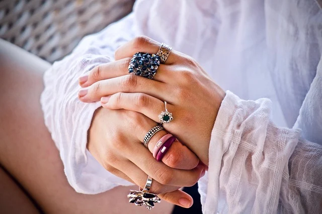 A person wearing multiple gemstone and silver rings on their hands