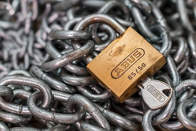 A brass padlock with a key on metal chains