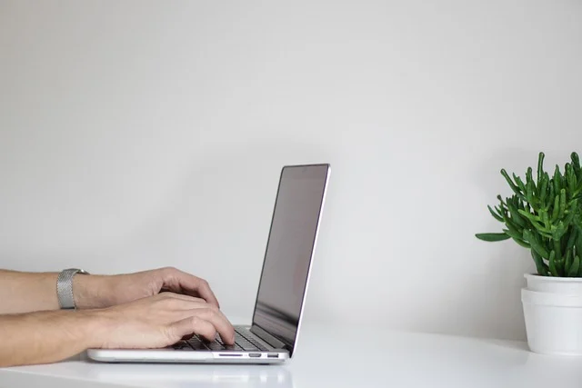 A person typing on a laptop computer at a desk