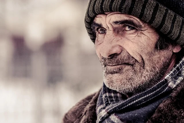Close-up portrait of an older man wearing a beanie and winter coat