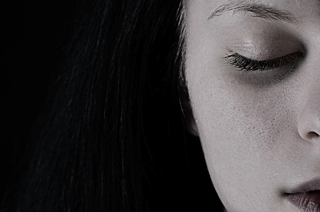 Close-up of a woman's face with soft, smoky eye makeup and a berry-toned lipstick.