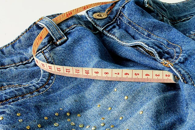 A measuring tape placed around a pair of denim jeans