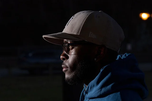 Side profile of a man wearing a cap and blue hoodie