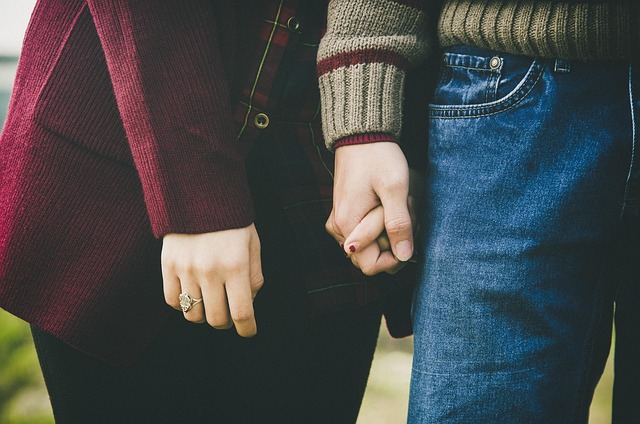 Couple holding hands walking on a beach in stylish casual outfits