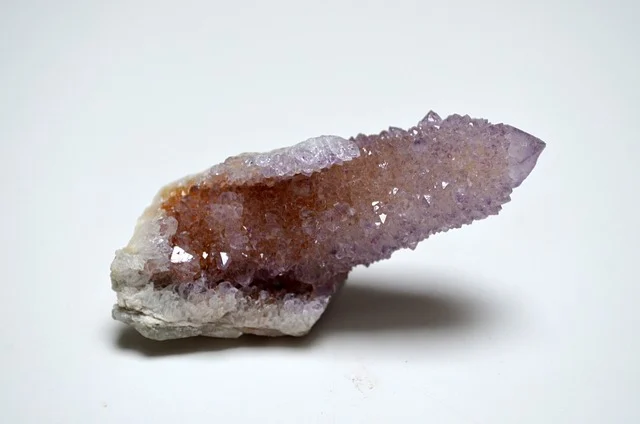 A raw purple spirit quartz crystal on a white background