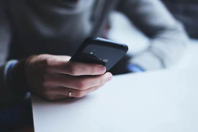 A person holding and using a smartphone at a desk