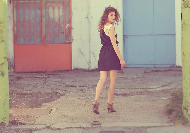 A woman with curly hair wearing a short black dress