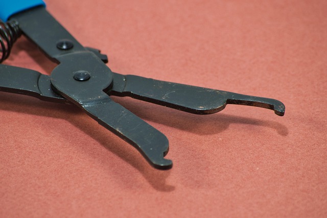 Hands using tweezers to pull threads from a cut in a pair of jeans