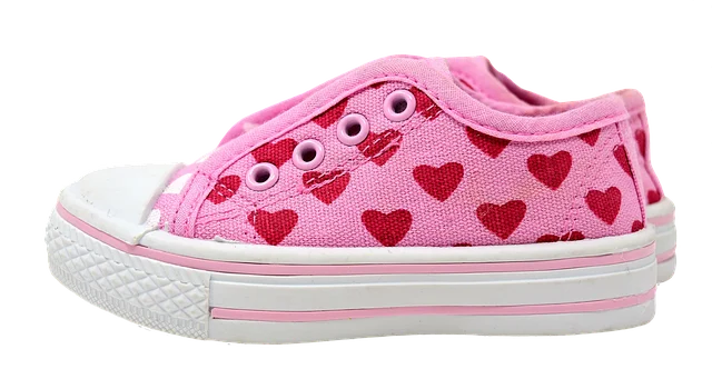 A pink canvas toddler sneaker with red heart patterns