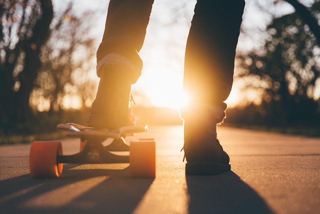 A person's legs and feet with a skateboard at sunset