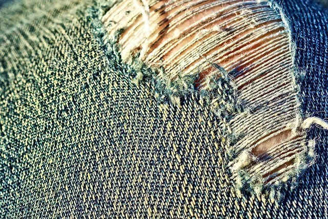Extreme close-up of ripped and distressed denim fabric