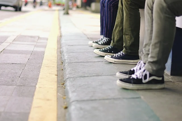 People sitting on a curb wearing black canvas sneakers