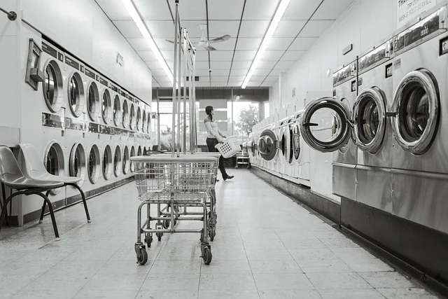 A laundromat with row of washing machines and laundry carts