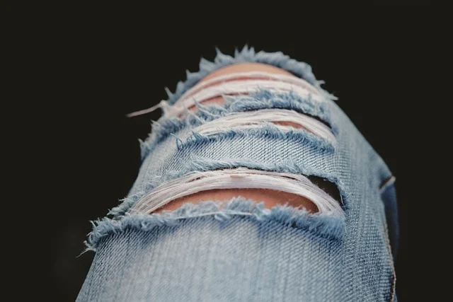 Close up of ripped blue denim jeans at the knee