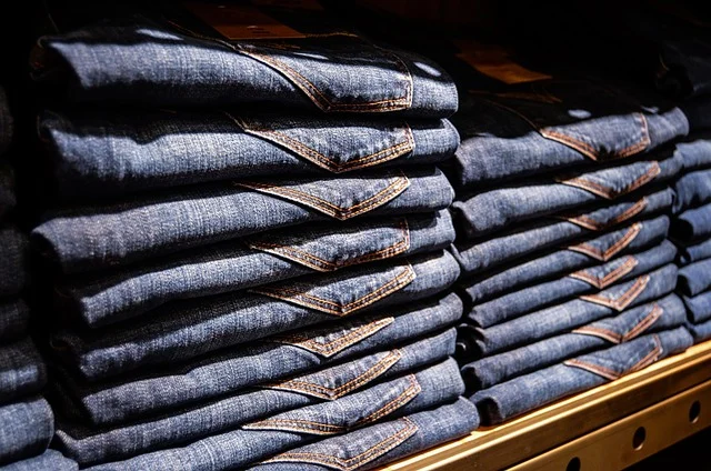 Stacks of folded blue denim jeans on a shelf