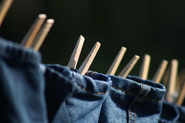 Blue jeans hanging on a clothesline with wooden clothespins