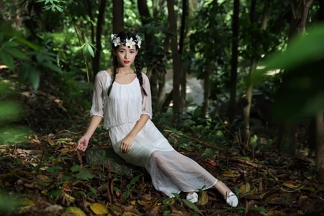 A woman wearing a white dress and floral crown in a forest