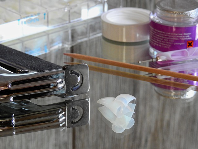 A nail technician applying chrome powder to a client's nail using a silicone tool.
