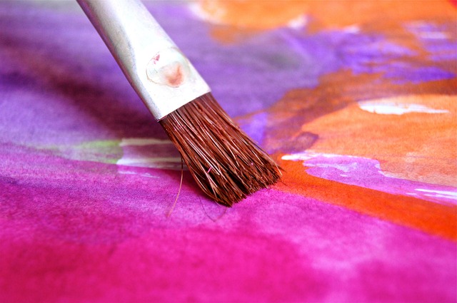 A person with a vibrant watercolor lotus flower tattoo on their arm, showcasing rich color blending.