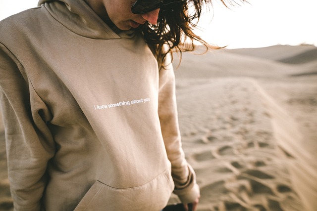 Person wearing a beige oversized hoodie with dark jeans and white sneakers.