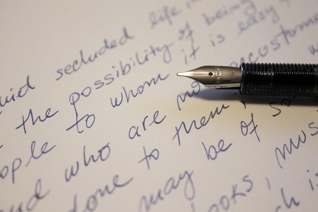 Person writing in a journal next to a laptop on a clean desk