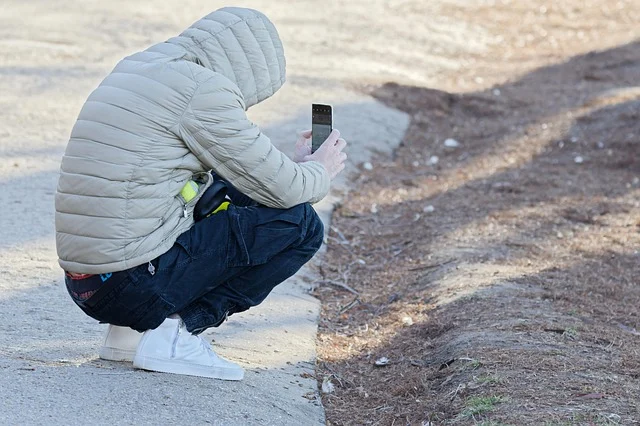 A person crouching outdoors while wearing a hooded puffer jacket