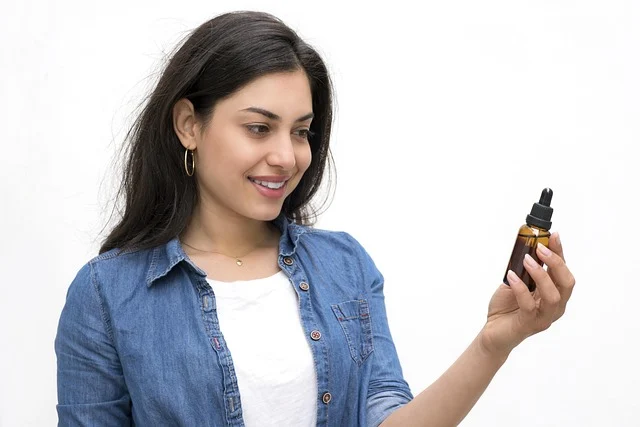 A woman holding and looking at a skincare serum dropper bottle