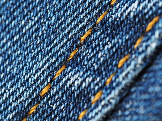 Extreme close up macro shot of blue denim fabric with orange stitching